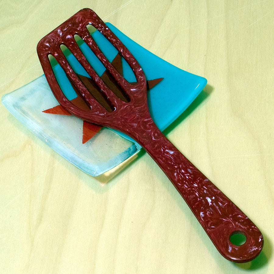 a red plastic comb sitting on top of a blue plate