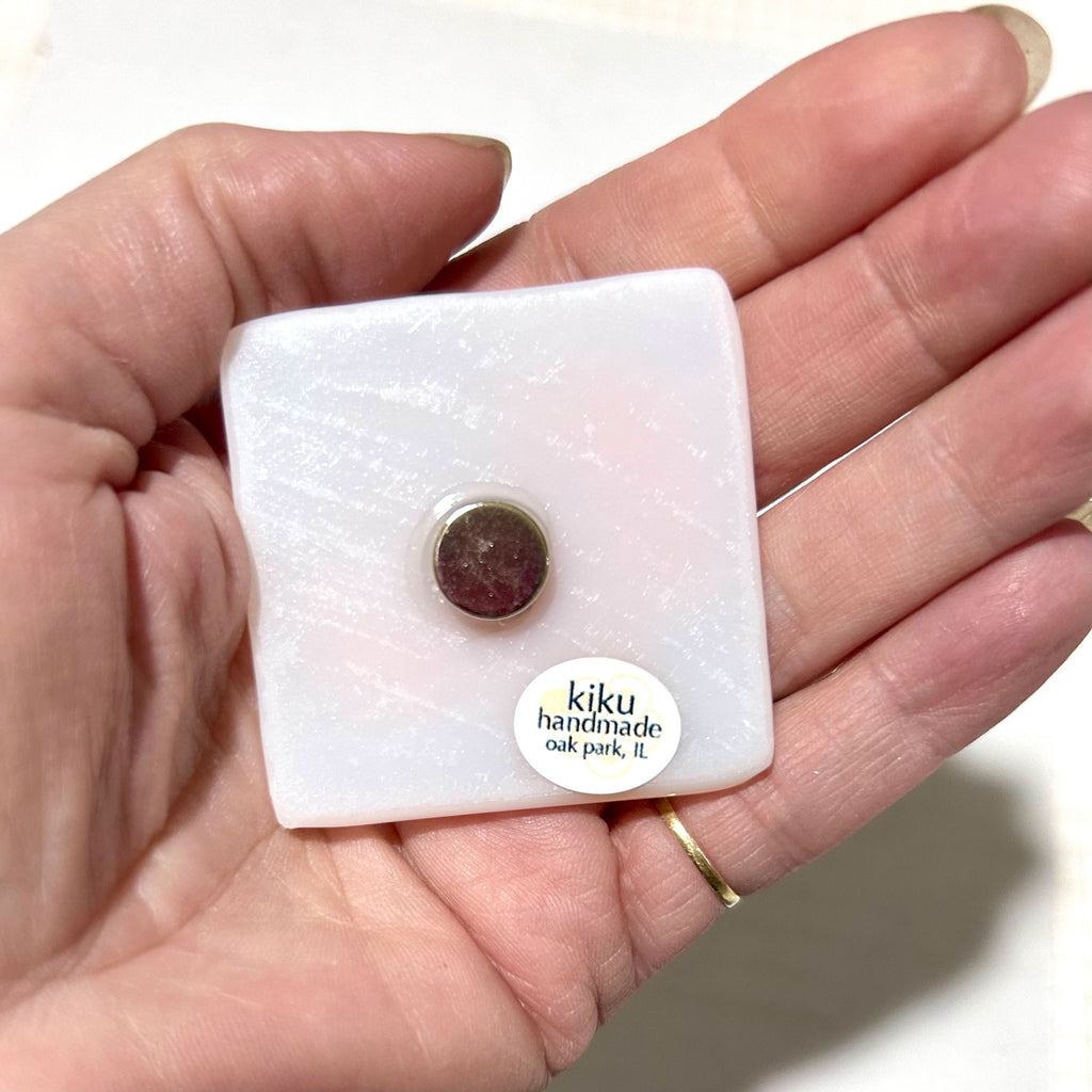 a person holding a small square piece of jewelry