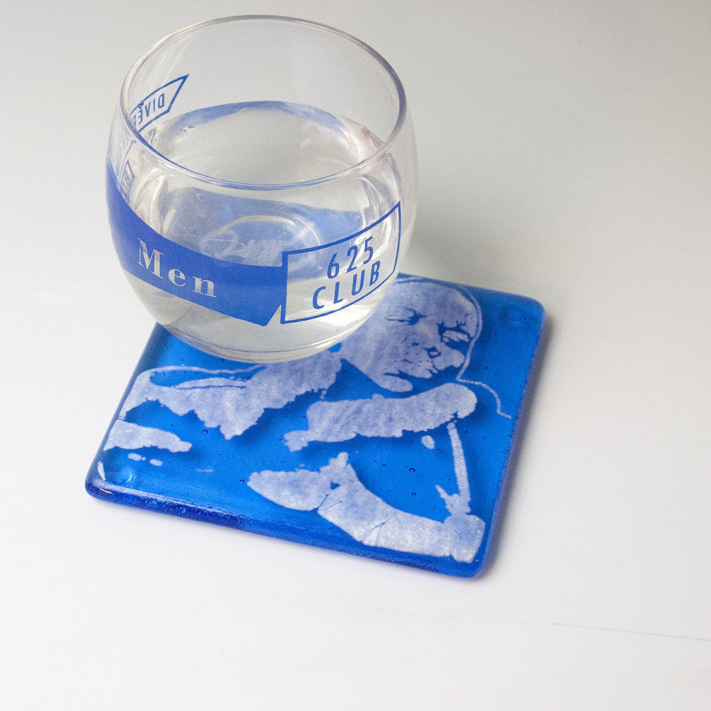 a glass of water sitting on top of a blue coaster