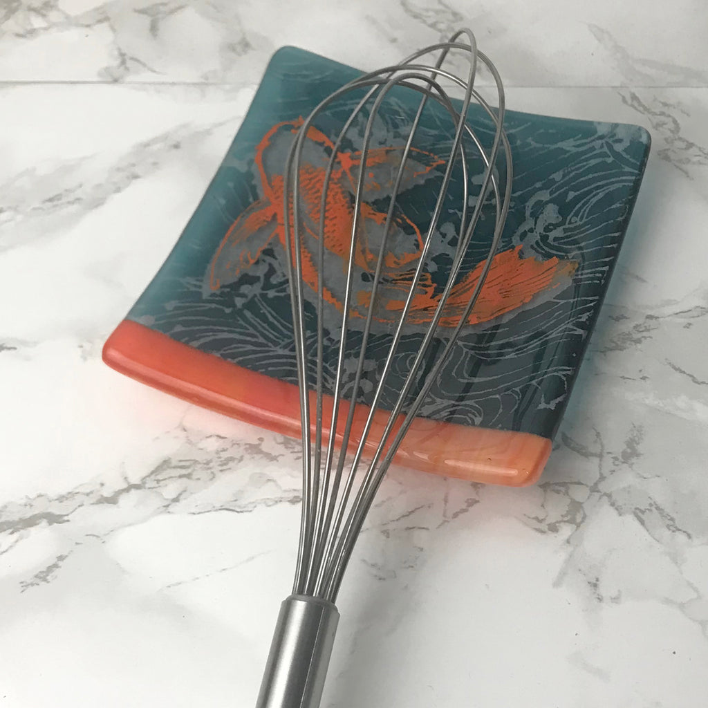 a whisk on a marble counter top next to a metal whisk