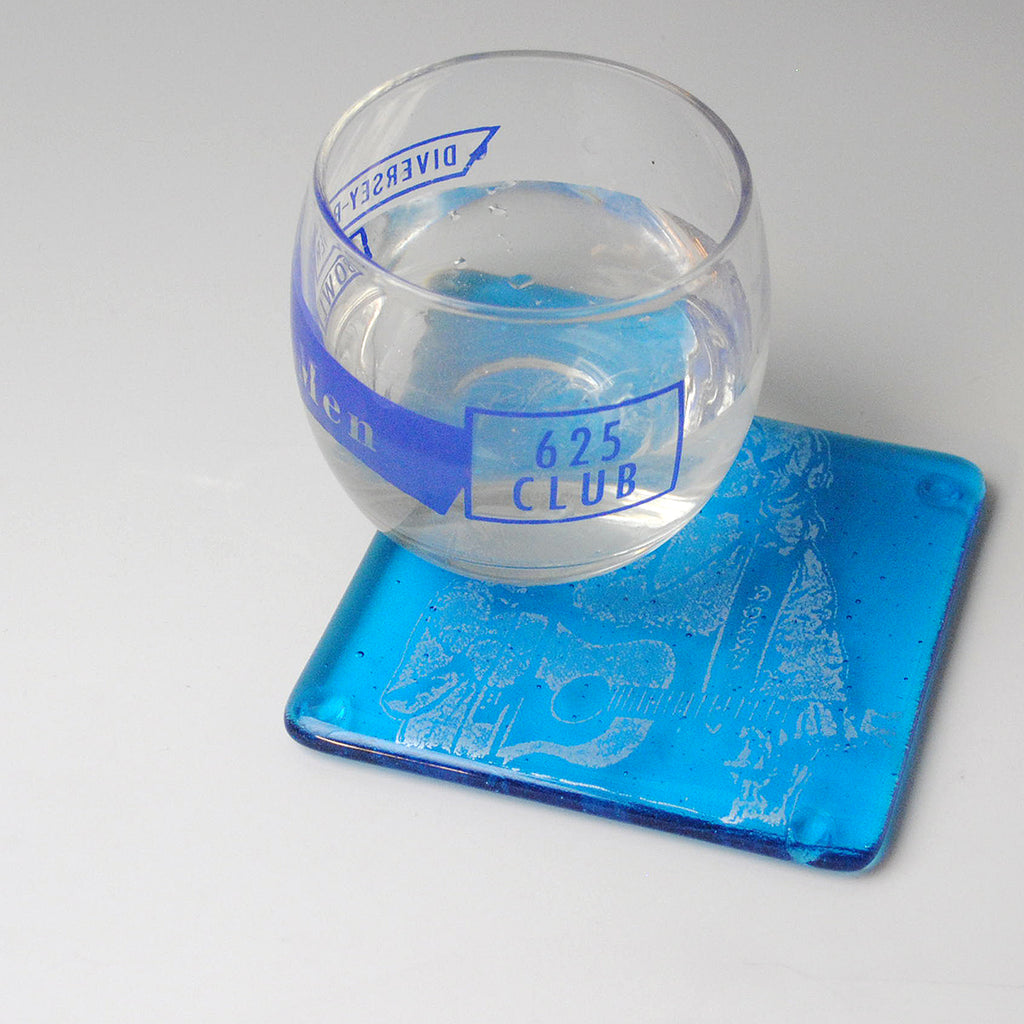 a glass of water sitting on top of a blue coaster