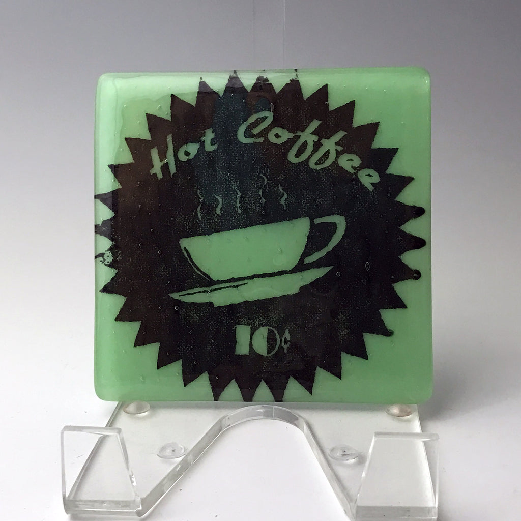 a green glass coaster with a picture of a coffee cup