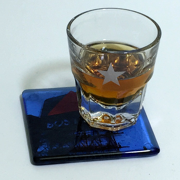 a glass of whiskey sitting on top of a blue coaster