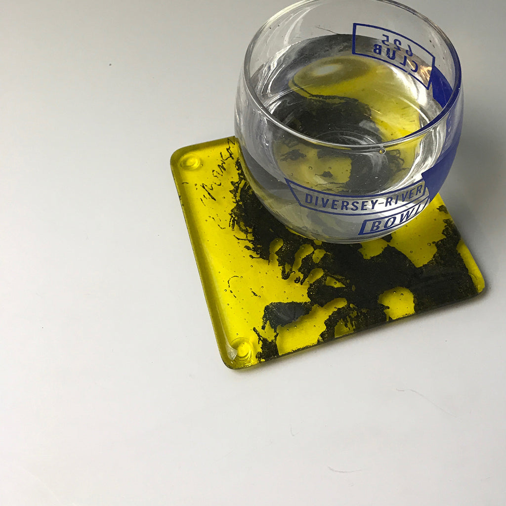 a glass of water sitting on top of a yellow coaster