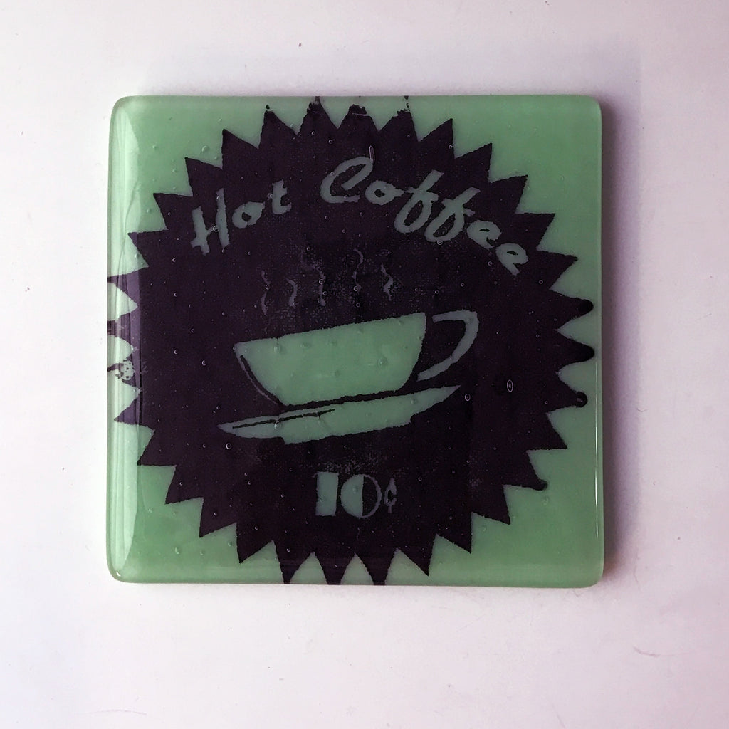 a green glass coaster with a picture of a coffee cup