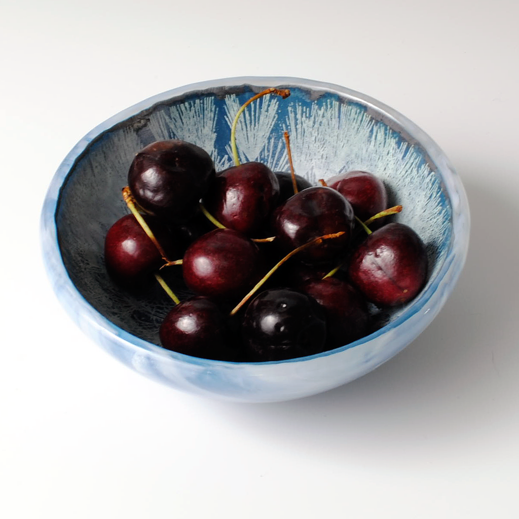 a bowl filled with cherries on top of a table