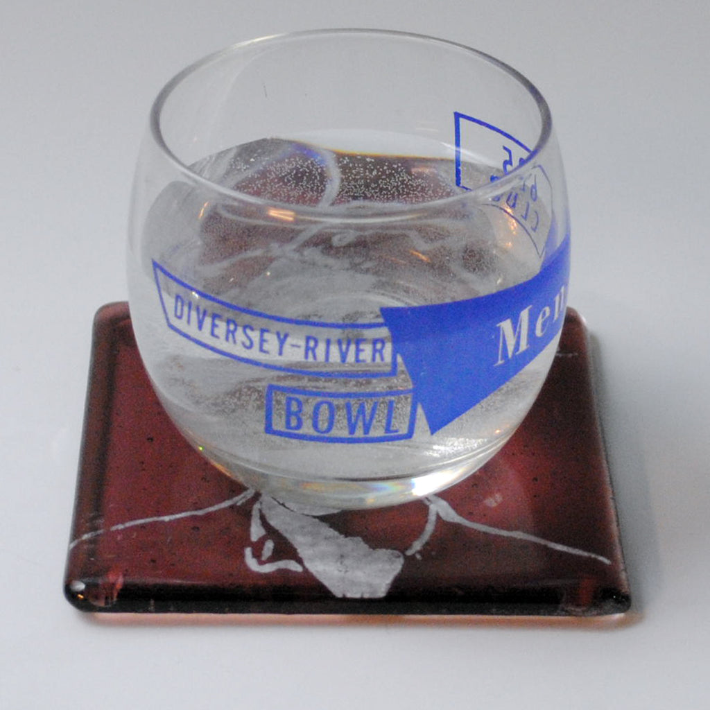 a glass filled with water sitting on top of a coaster