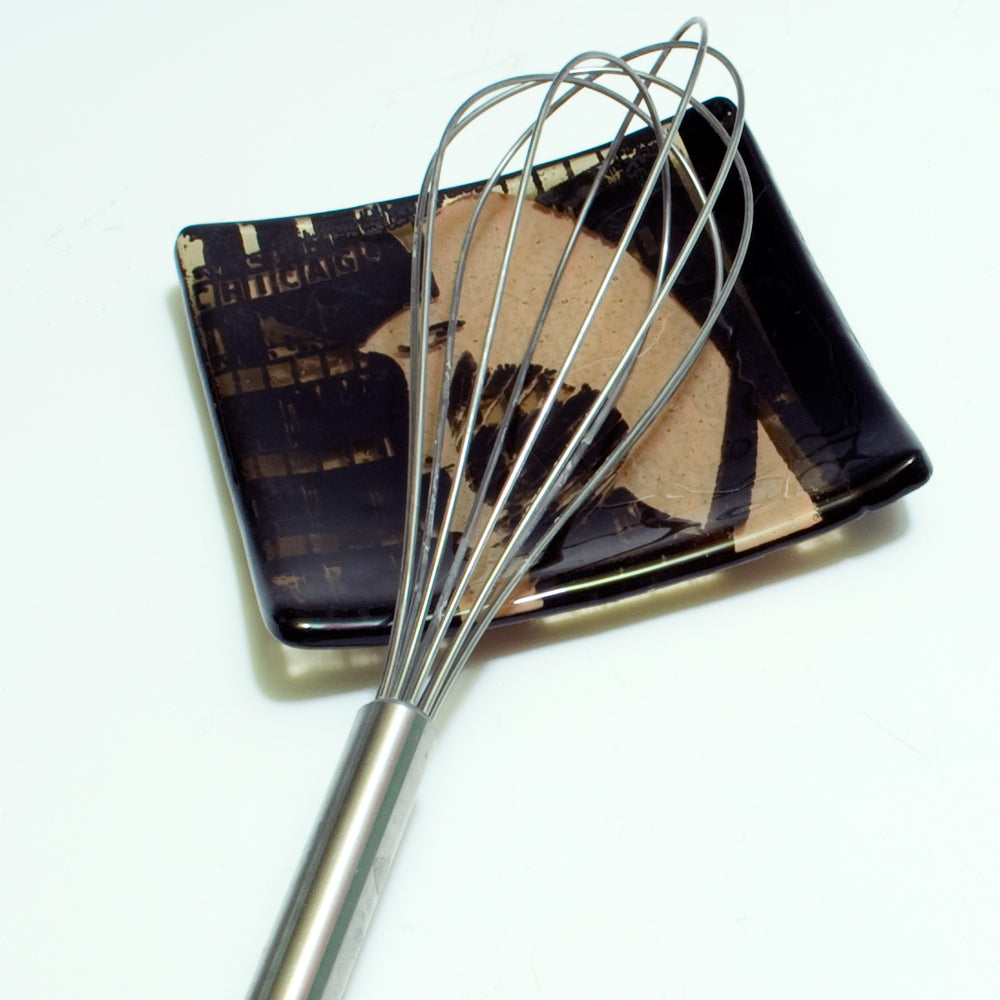 a metal whisk sitting on top of a black plate