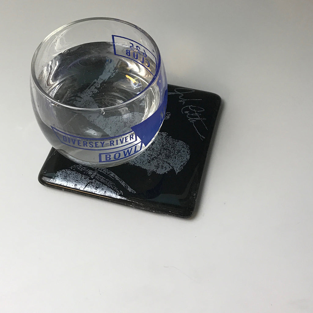 a glass of water sitting on top of a coaster