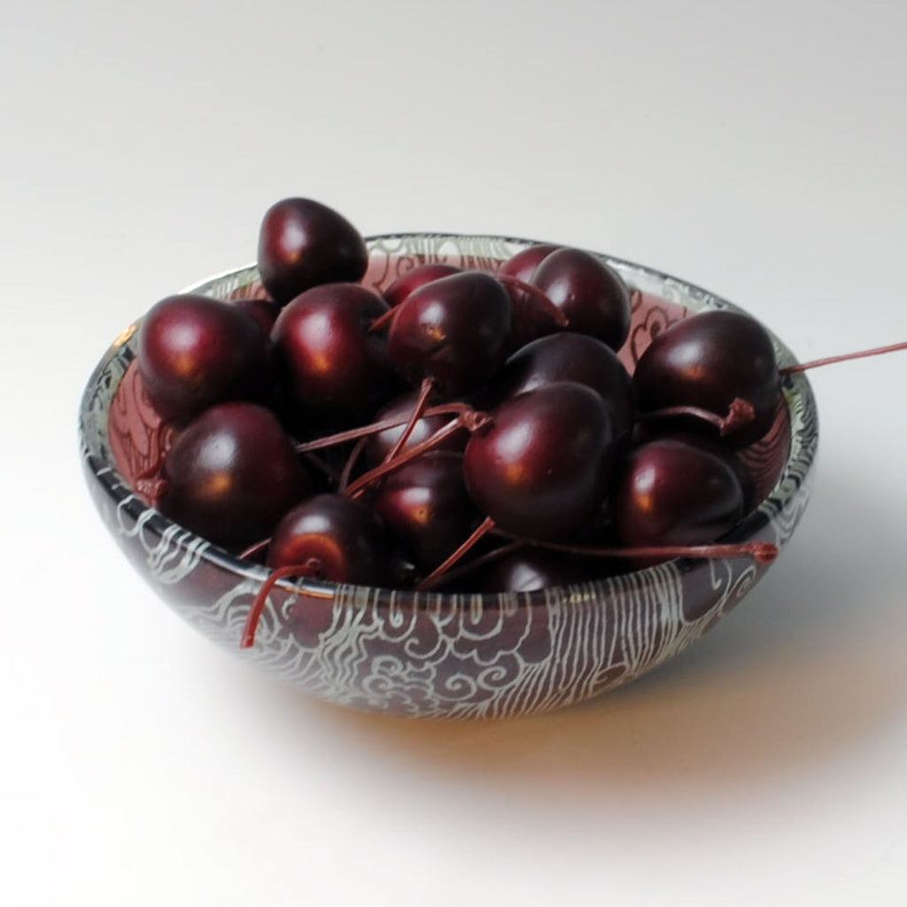 a bowl of cherries on a white table