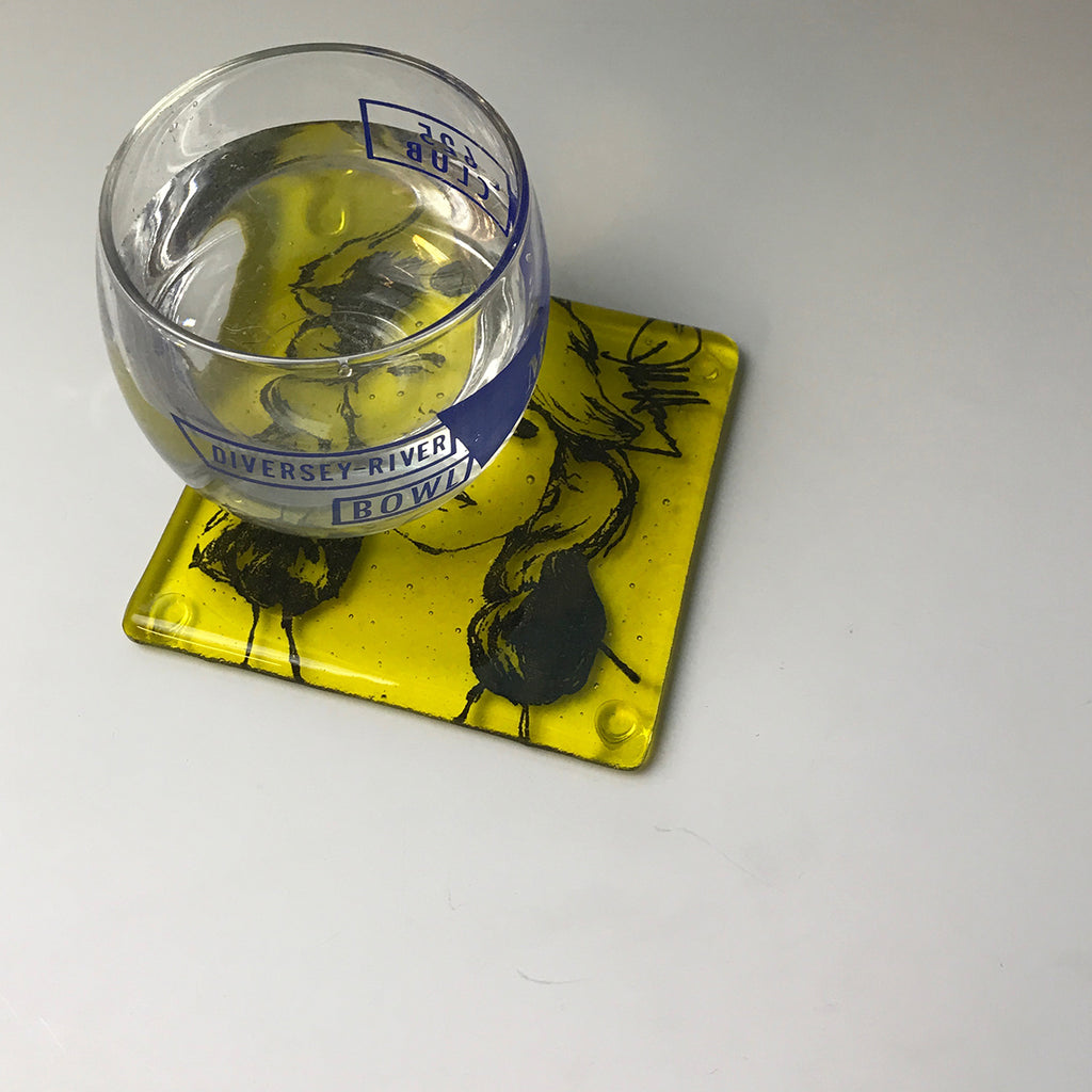 a glass of water sitting on top of a yellow coaster