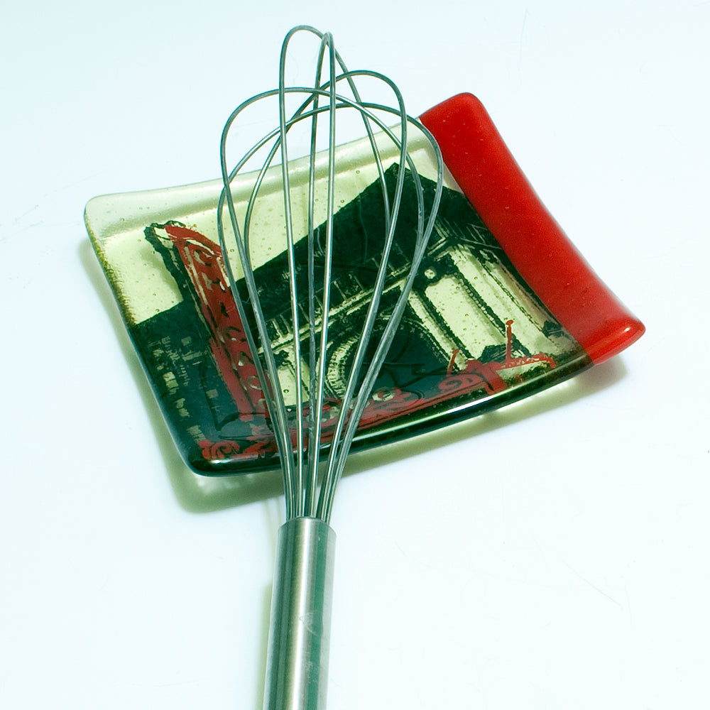 a whisk on a plate with a red handle