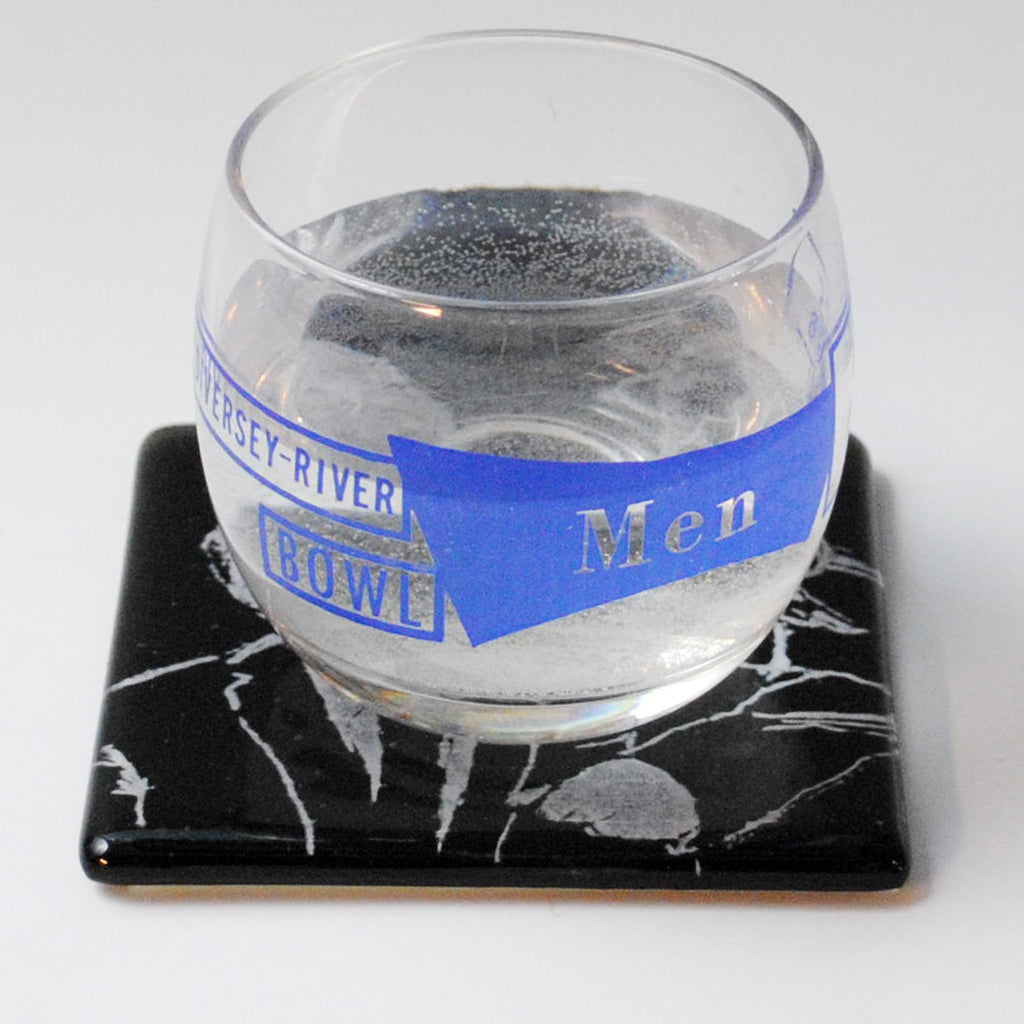 a glass of water sitting on top of a coaster