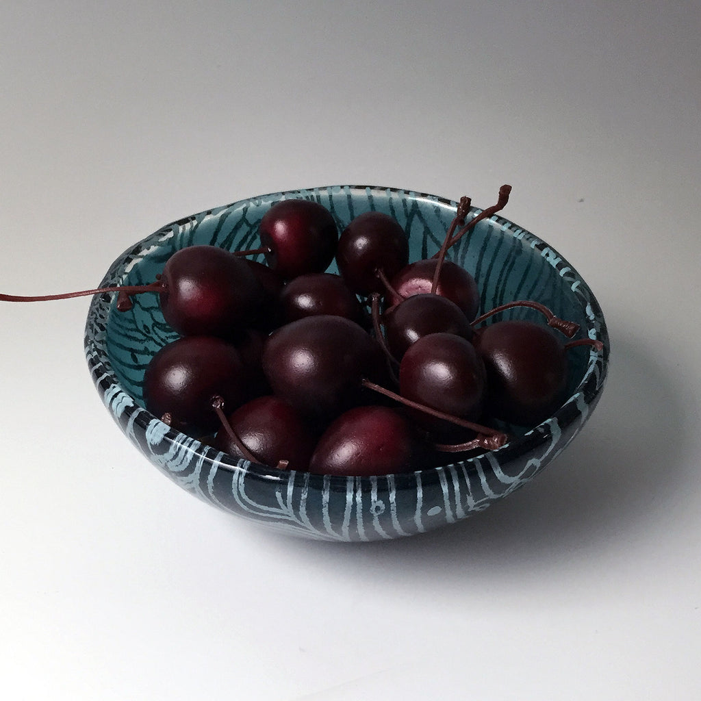 a bowl of cherries on a white table