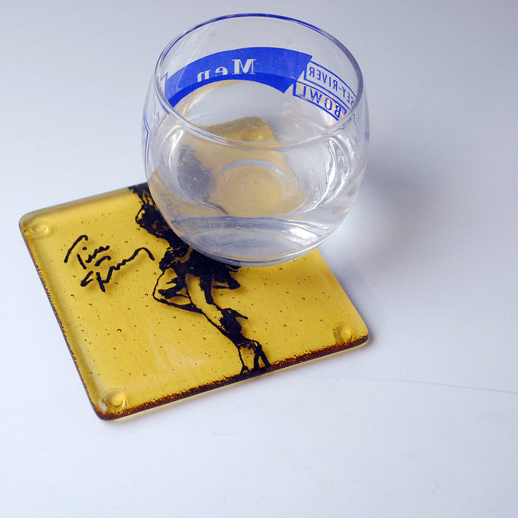 a glass filled with water sitting on top of a yellow coaster