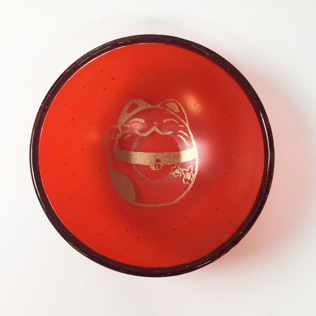 a red bowl with a gold decoration on it