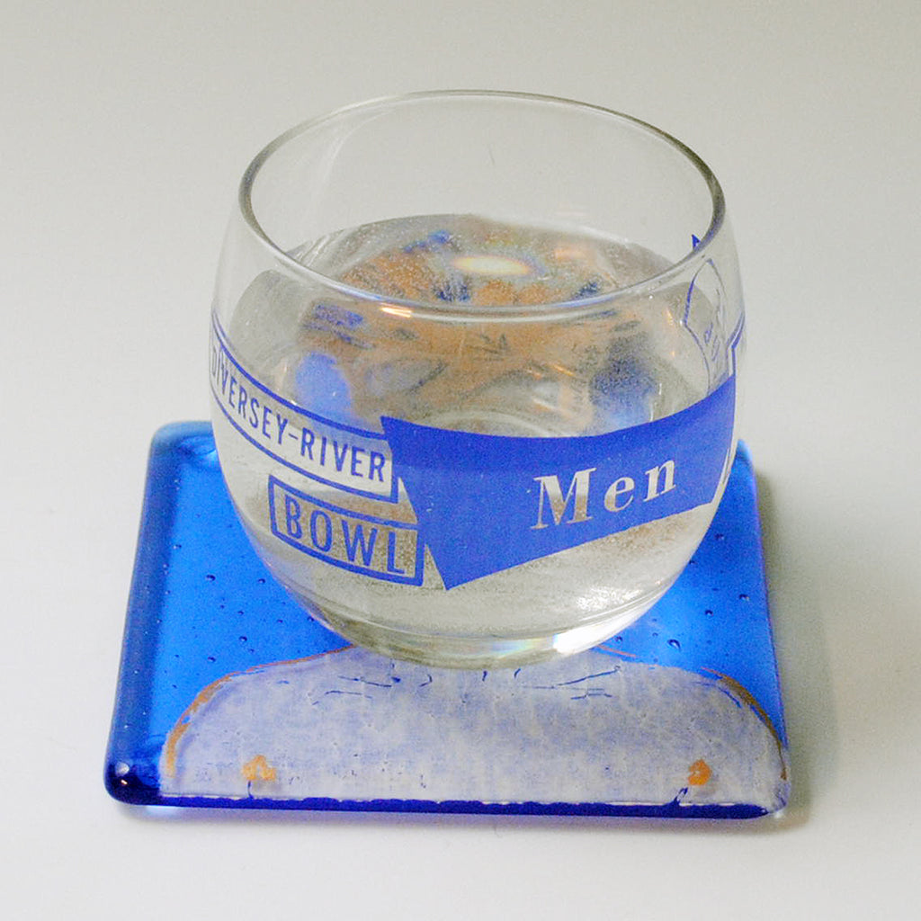 a glass of water sitting on top of a blue coaster