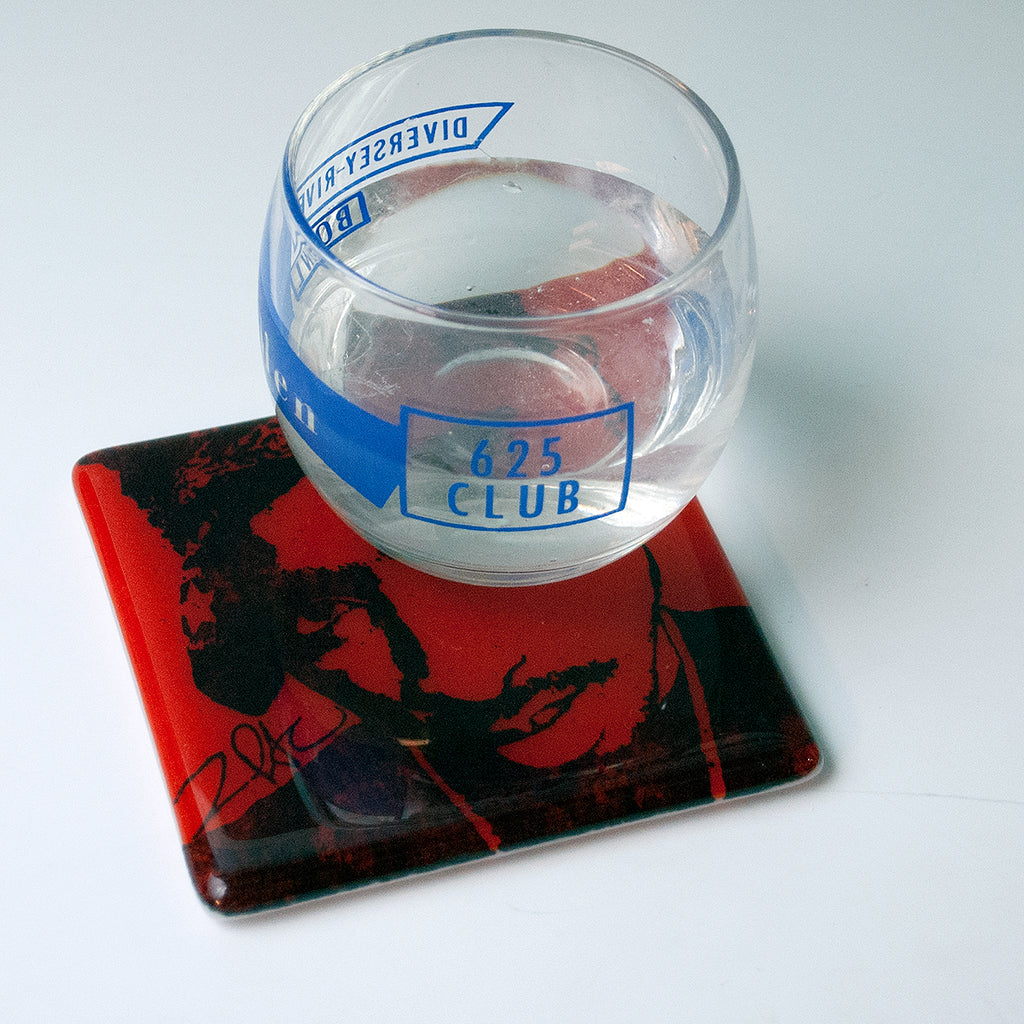 a glass of water sitting on top of a coaster