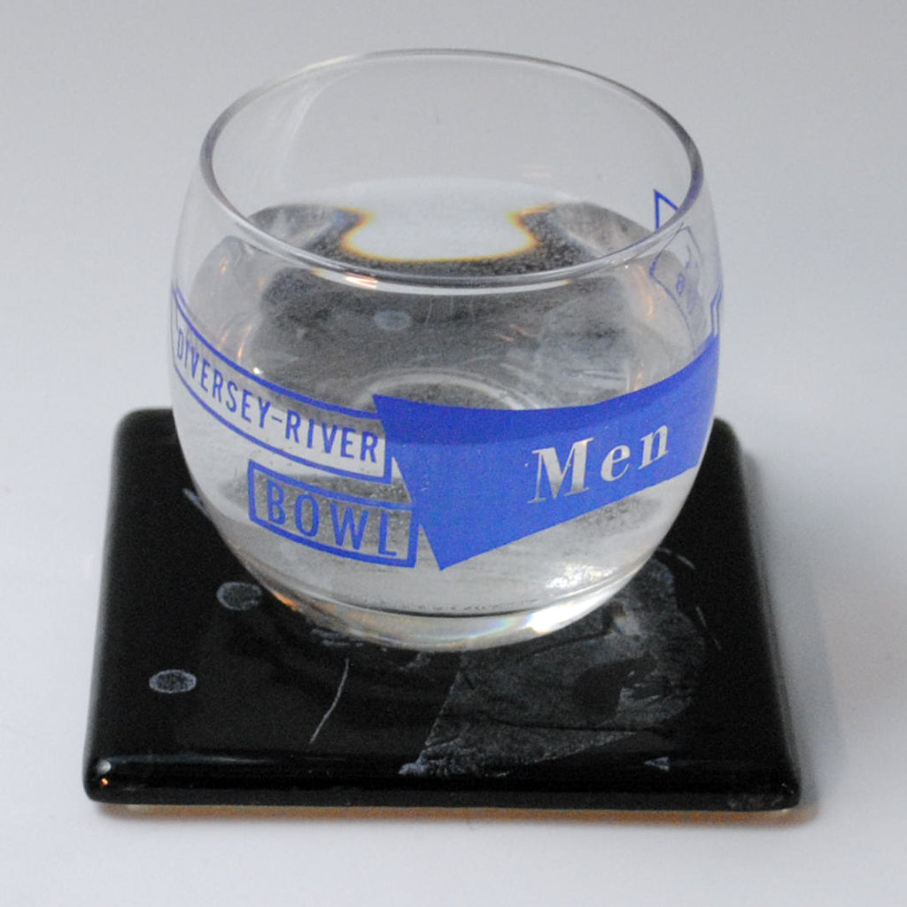 a glass of water sitting on top of a coaster