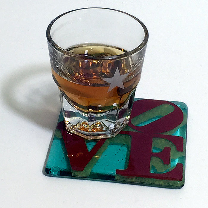 a glass of alcohol sitting on top of a coaster