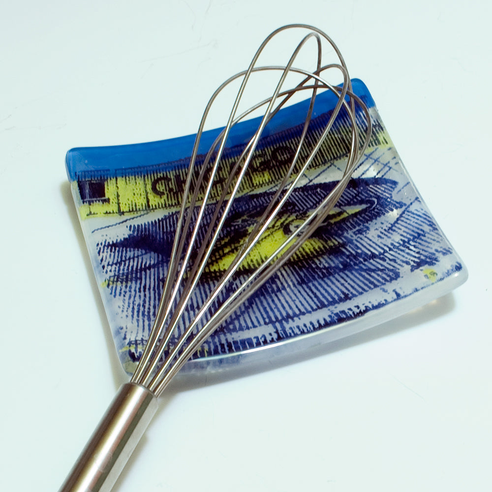 a metal whisk on a blue and white plate