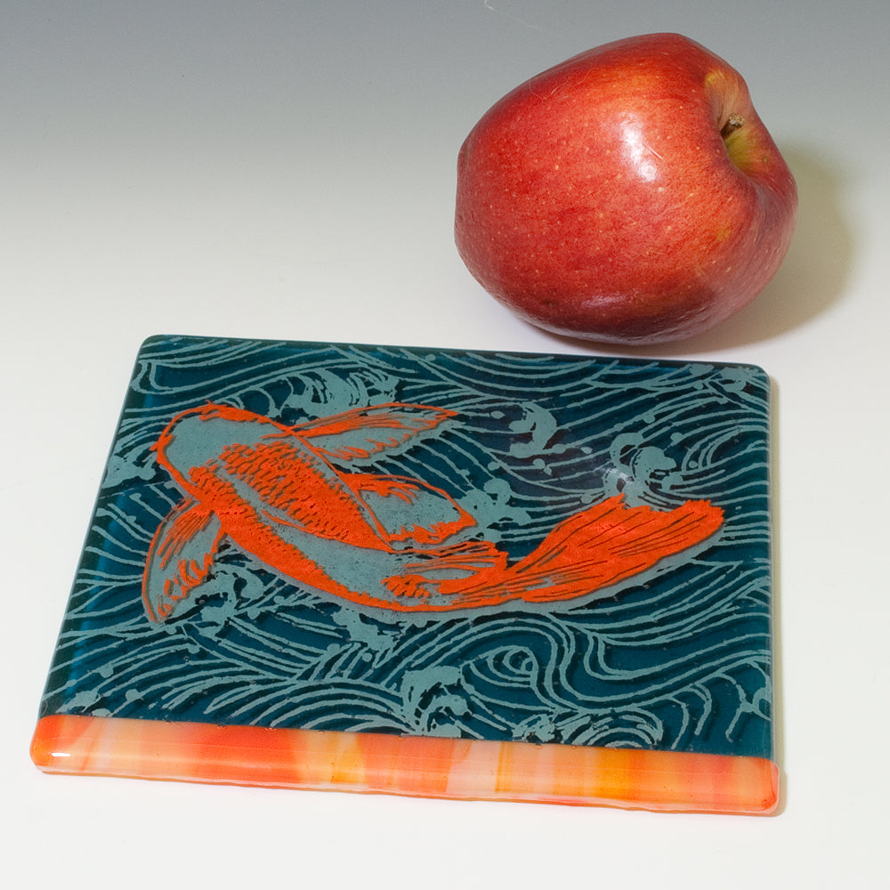 a red apple sitting next to a blue and orange coaster