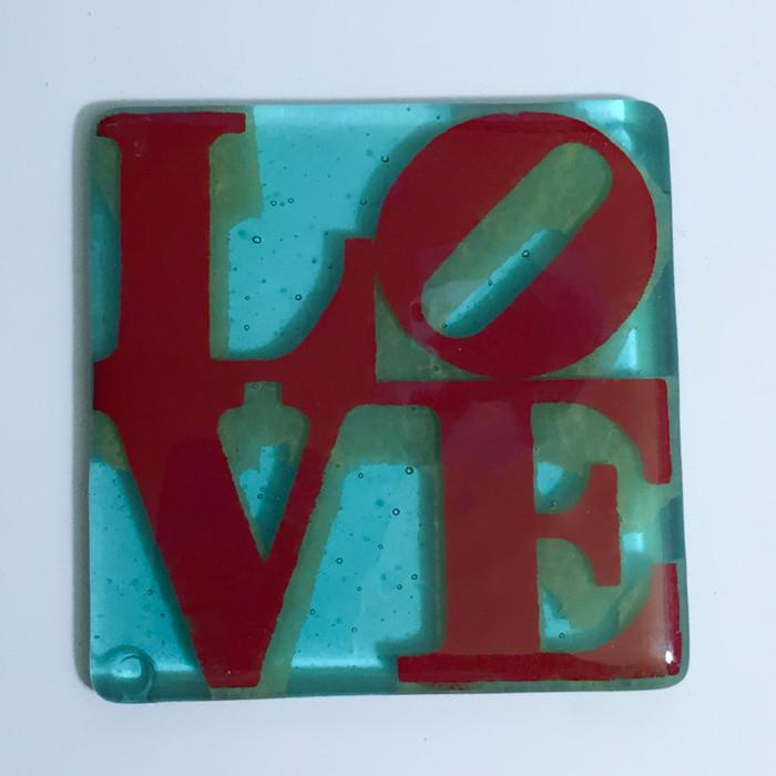 a red and blue glass tile with the word love on it